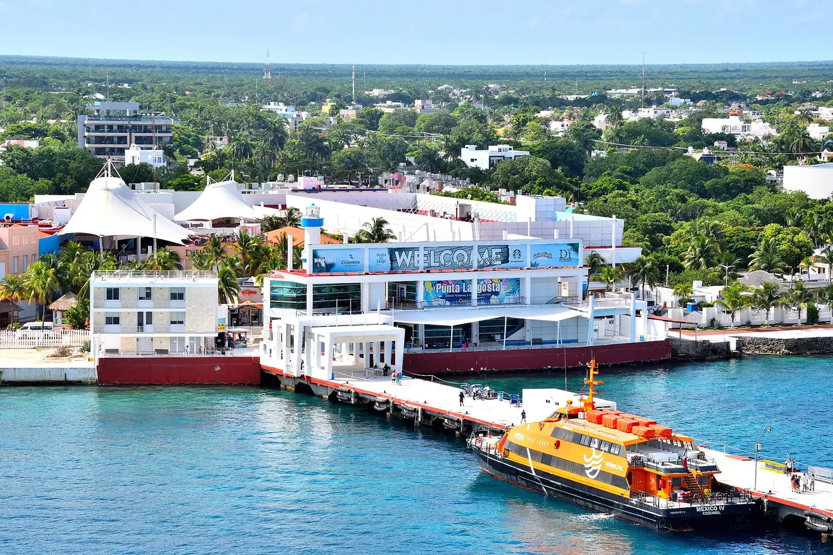 An aerial view of the Punta Langosta cruise terminal in Cozumel, with a yellow ferry beside a long pier